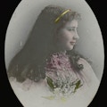 Helen Keller wearing dress with lace at collar and holding flowers side view facing right for a colored, head and shoulders portrait.