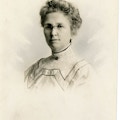 A head and shoulders portrait of a Horace Mann School female oral educator with glasses and a curled up-do hair style.