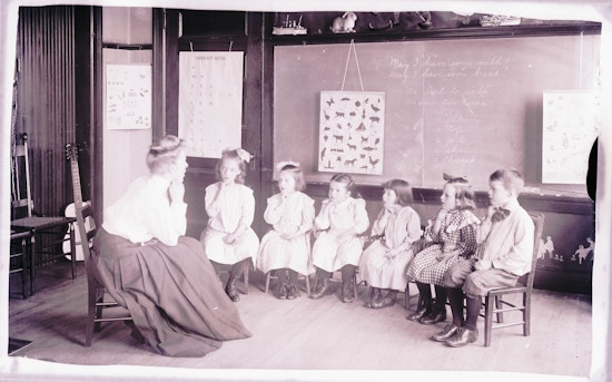 Six deaf students all sitting facing camera in classroom while one female teacher instructs the lesson.