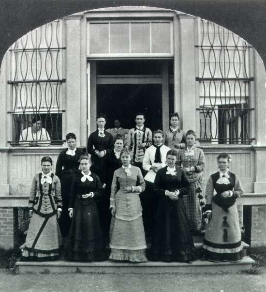Fourteen women pose on the steps of the Willard Asylum.