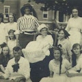Outdoor photograph of fifteen patients and staff dressed in costume, at the Rome State School for the Mentally Retarded.  A woman holds a sign that reads champions.