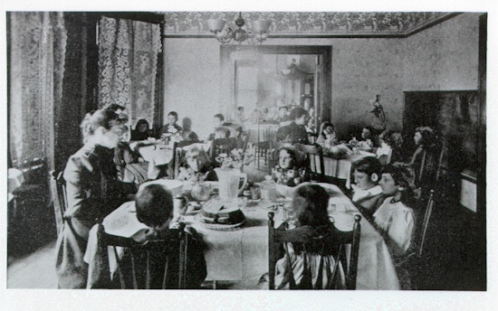 Young children of the McCowen School dine in a small parlor. Each table of children has a faculty member present.