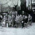 A newspaper photograph of about twenty people, about half of whom are in wheelchairs.