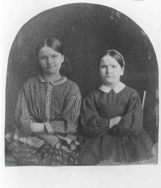 Two women pose with their arms crossed against their chests