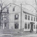 Photograph of the Cogswell House, a large townhouse, with a horse drawn carriage on the street in front.