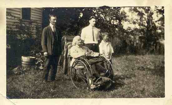 An elderly woman in a wheelchair with a boy and two men nearby.