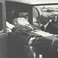 The author, strapped on a stretcher, enters an automobile.
