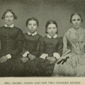 A photographic portrait of a women in a plain black dress with her three daughetrs, one wearing dark glasses.