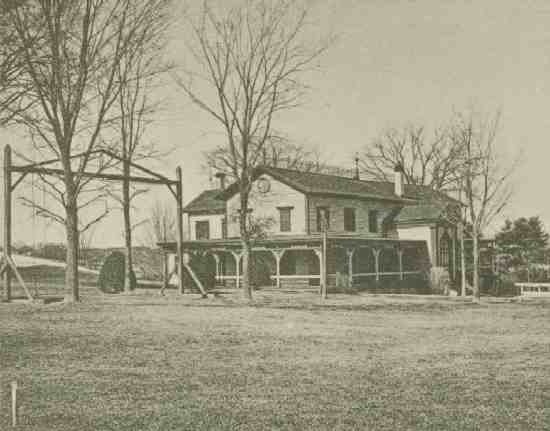 A house with porch, structure with rope swing in front.