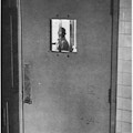 A man seen through the barred window of a door.