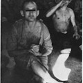 Two partially dressed men sitting on a floor,