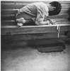 A boy tied to a wooden bench.