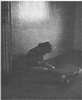 A person sitting on a floor looking at their hands.