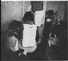 Children sitting on a floor in a dilapidated room.