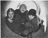 Three boys playing inside large pipe.