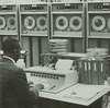 An African American man works at an early computer.