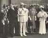 Roosevelt, holding the arm of a man in uniform, speaks with the King.  Eleanor Roosevelt and Queen Elizabeth stand nearby.