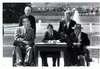 George Bush in front of White House sitting at table signing ADA; with a priest, a woman, and two men in wheel chairs