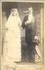 A large man and woman.  She wears a wedding dress.
