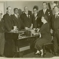 Keller sitting with hands on Visagraph, braille machine, men in suits stand around machine, Robert Irwin far right