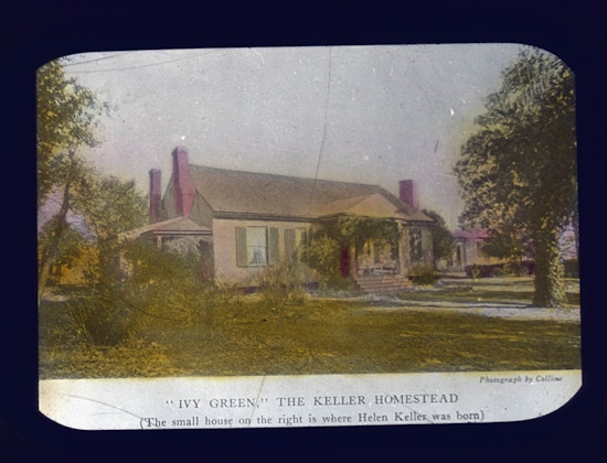 Helen Keller's childhood home, Ivy Green, in Tuscumbia, Alabama. The photograph caption reads, "Ivy Green, The Keller Homestead. The small house on the right is where Helen Keller was born".