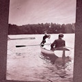 Helen Keller rowing in rowboat with one passenger each at the head and tail of the boat.