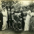 Family gather on a wedding day. Man at center in a wheelchair.