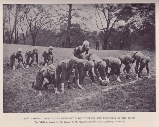 Boys playing football, in uniform.