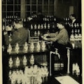 Five men working, surrounded by dozens of bottles.