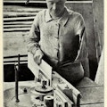 A man with one arm works on machine in a woodworking shop.