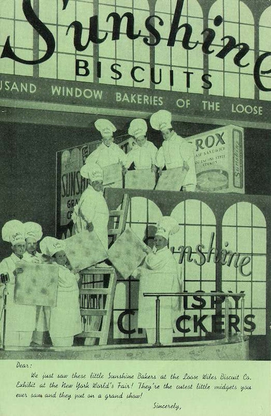 Photograph of short-statured people dressed as chefs holding up giant Sunshine crackers in front of giant cracker box at 1939 New York World's Fair.