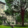 Color postcard of large building and lawn shaded by trees.