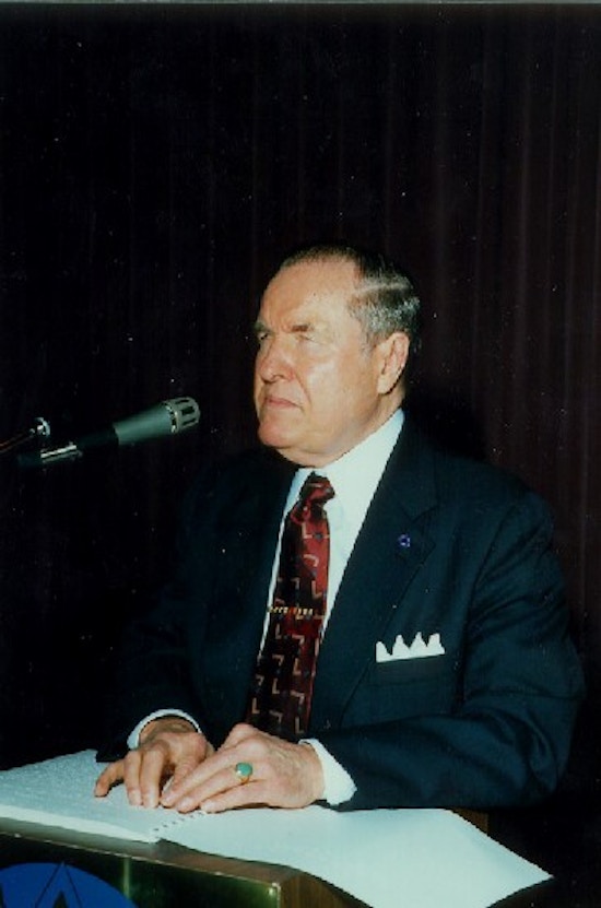 Jernigan at a sitting at a table in front of a microphone.