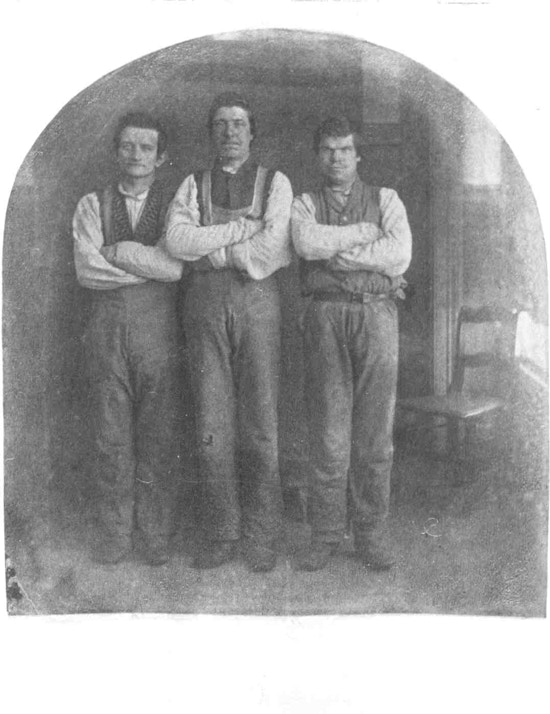 Three men stand with their arms folded across their chests.