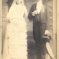 A large man and woman.  She wears a wedding dress.
