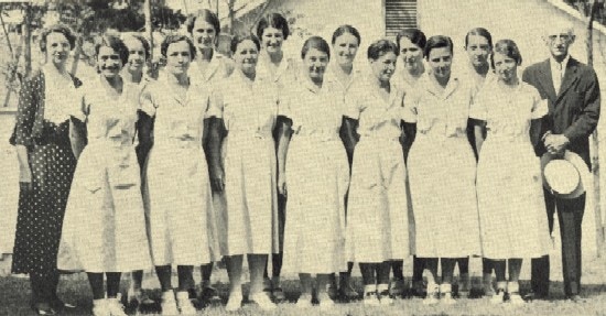 A group photo of women in uniform with an elderly man.