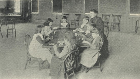 Seven children and a teacher sit around a table.