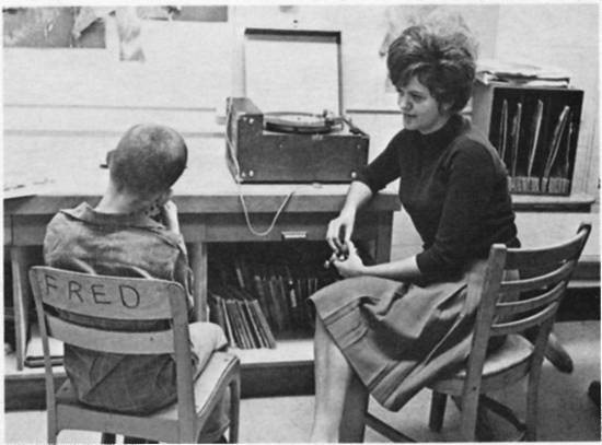 A boy, in a chair marked "Fred," sits next to a woman and a record player.