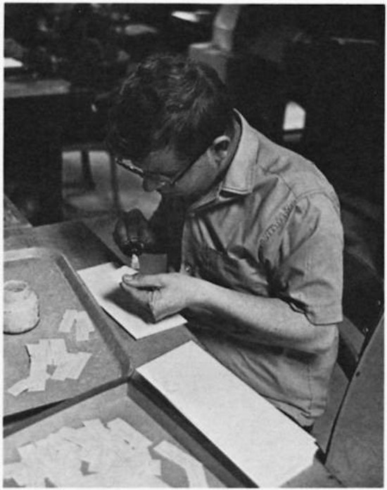 A young man gluing paper.