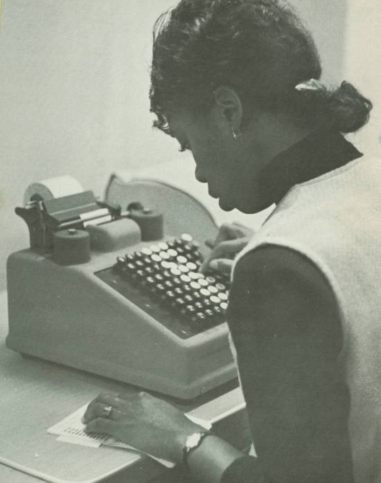 An African American woman working on an adding machine.