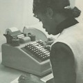 An African American woman working on an adding machine.