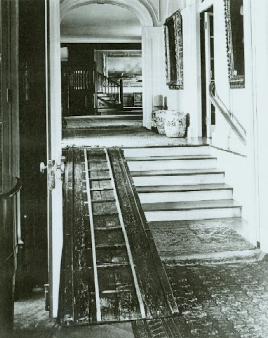 Wooden ramp along stairs in ornate Victorian house.